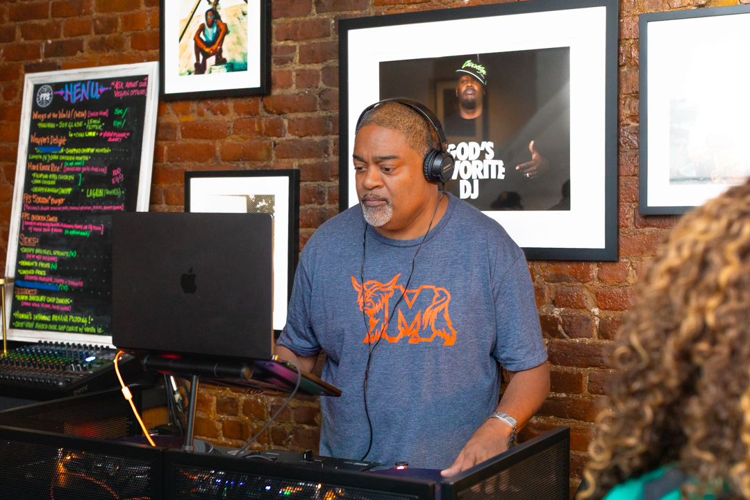 The DJ — headphones on, locked in, reading the room perfectly