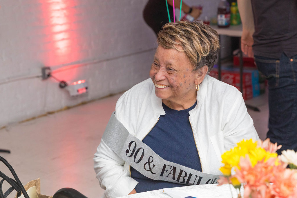 The 90-year-old honoree smiling with flowers in the foreground