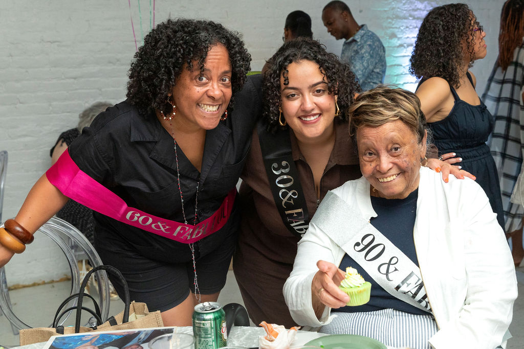 All three honorees together — 60, 30, and 90 sashes, cupcake in hand