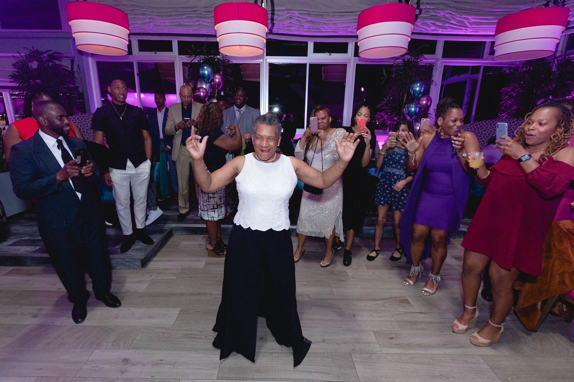 The dancing circle — guests ringing the honoree, phones raised, pure celebration