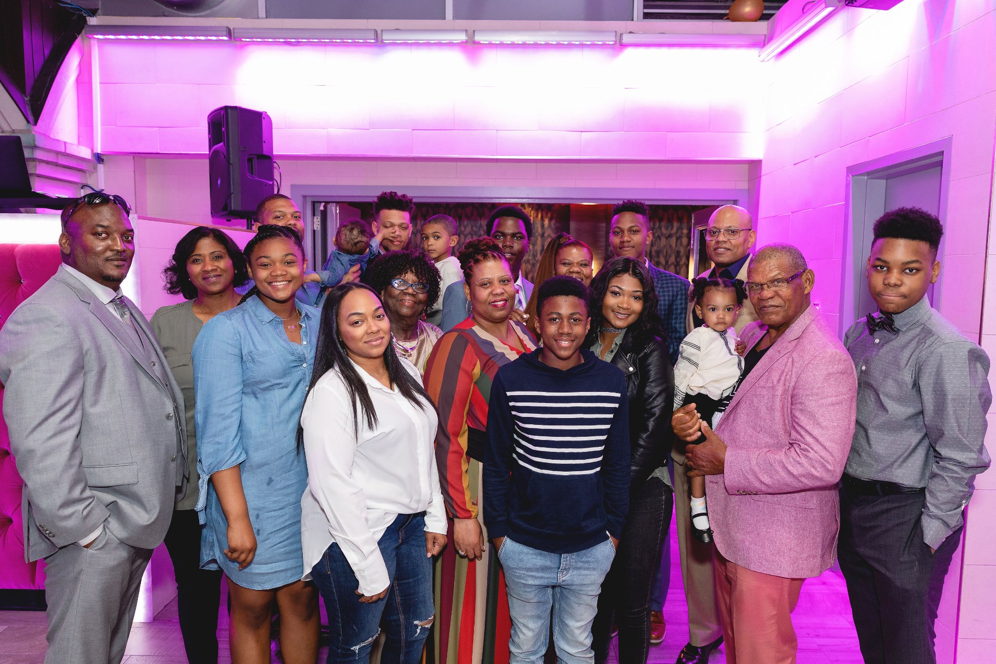 Honoree being spun on the dance floor — arms raised, laughing, blue light and balloons