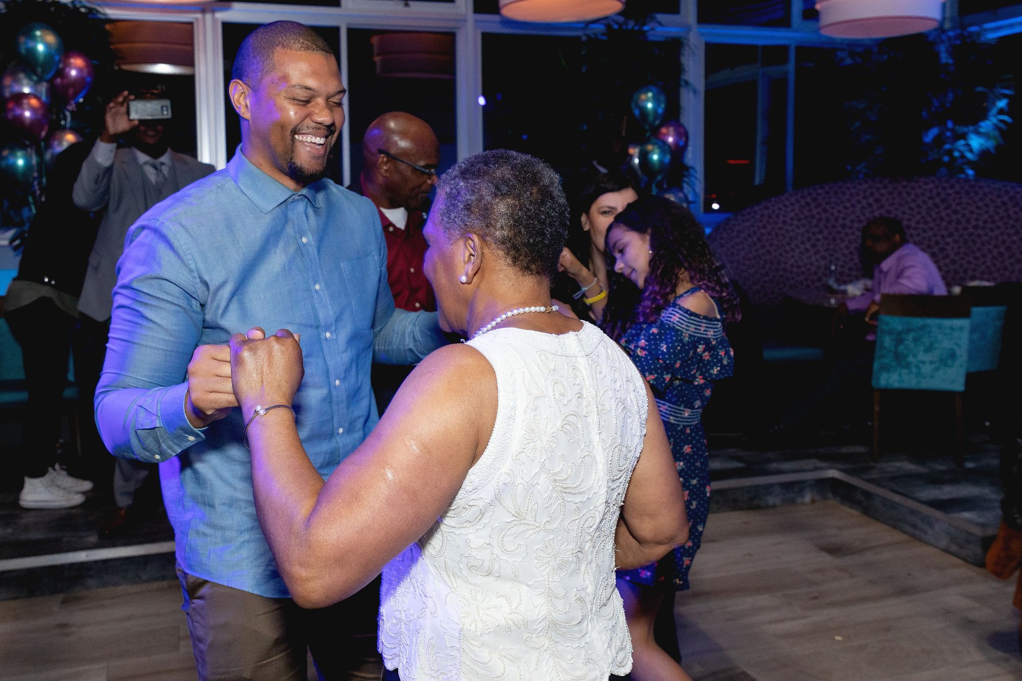 Selfie moment — honoree and guest cheek to cheek, purple light, warm connection