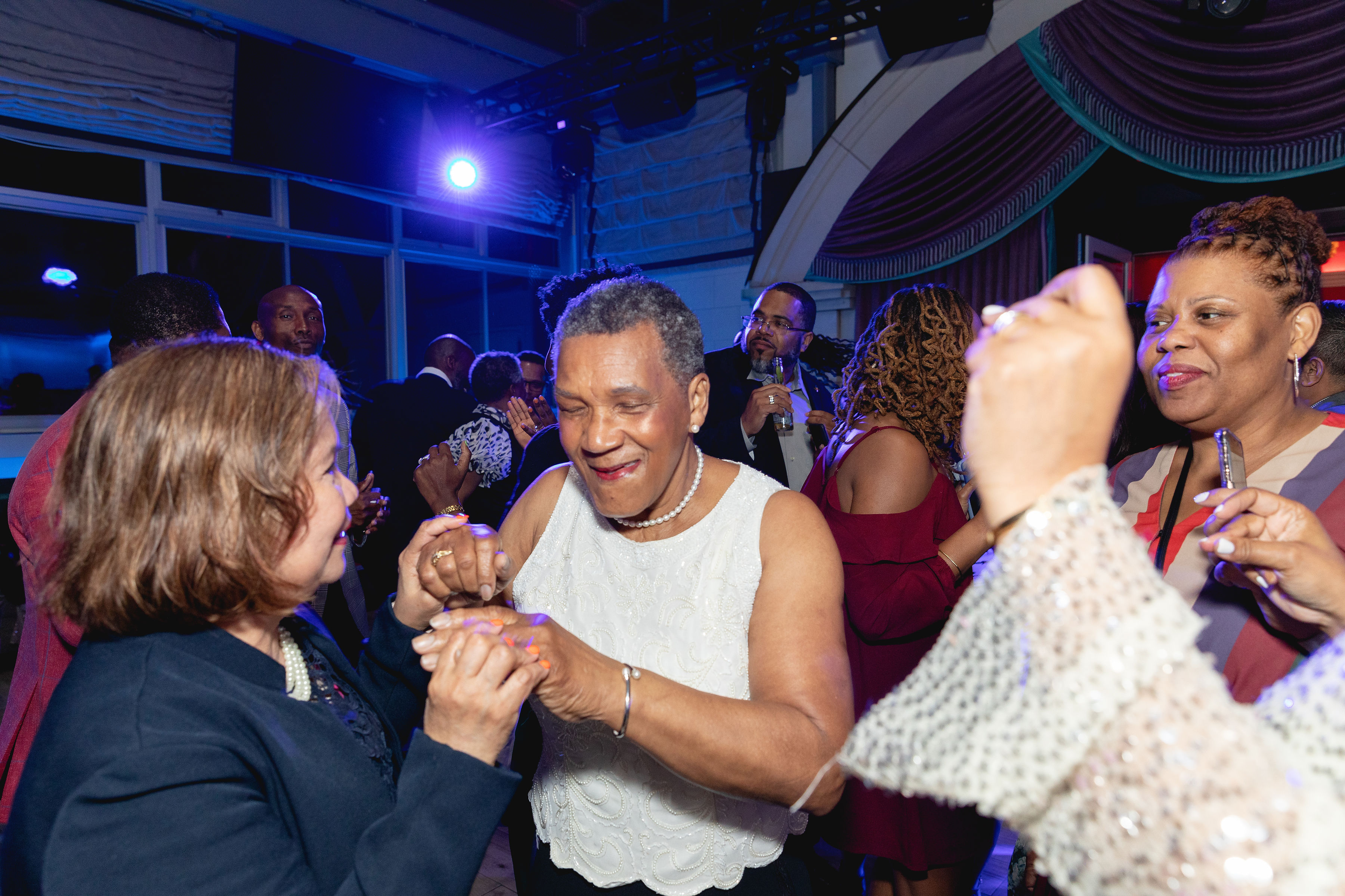 The honoree dancing with a woman — hands joined, eyes closed, fully in it