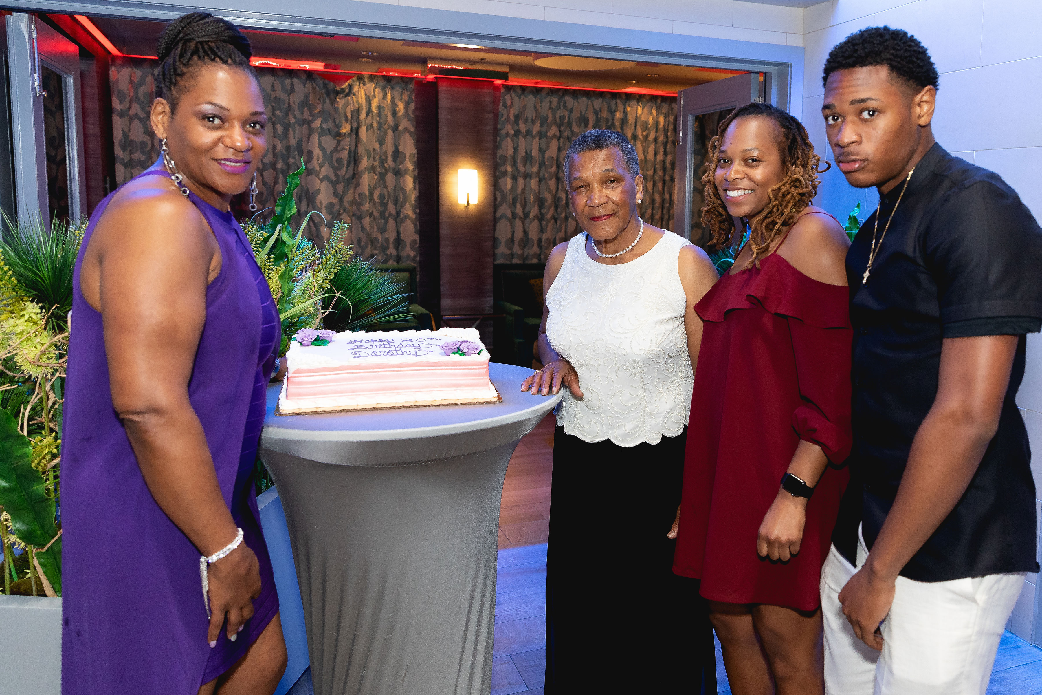 The honoree beside her birthday cake — family around her, the celebration at its warmest