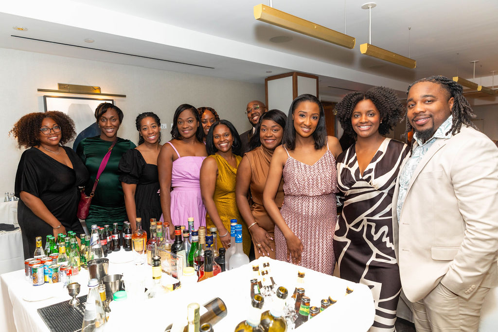 Large group of guests gathered and smiling at the bar at the end of the evening