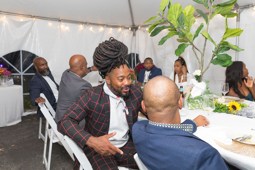 Guests at the dinner table under the white tent with string lights and florals