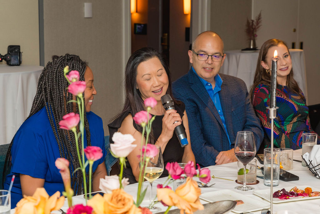 Woman speaking at the table, guests listening intently