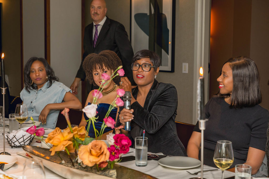 Woman speaking into a microphone at the dinner table