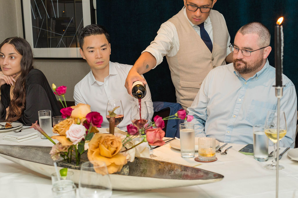 Red wine being poured, roses in foreground