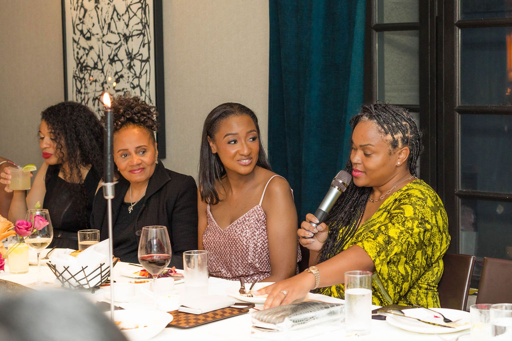 Guest speaking into microphone, attentive faces around her