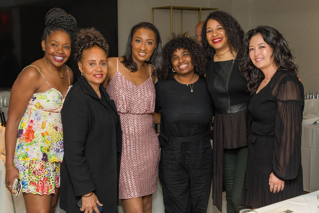 Group of six women posing together, relaxed and joyful