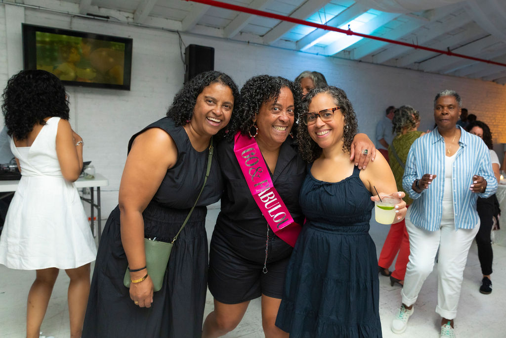 Three generations blowing birthday candles — 30, 60, and 90 sashes