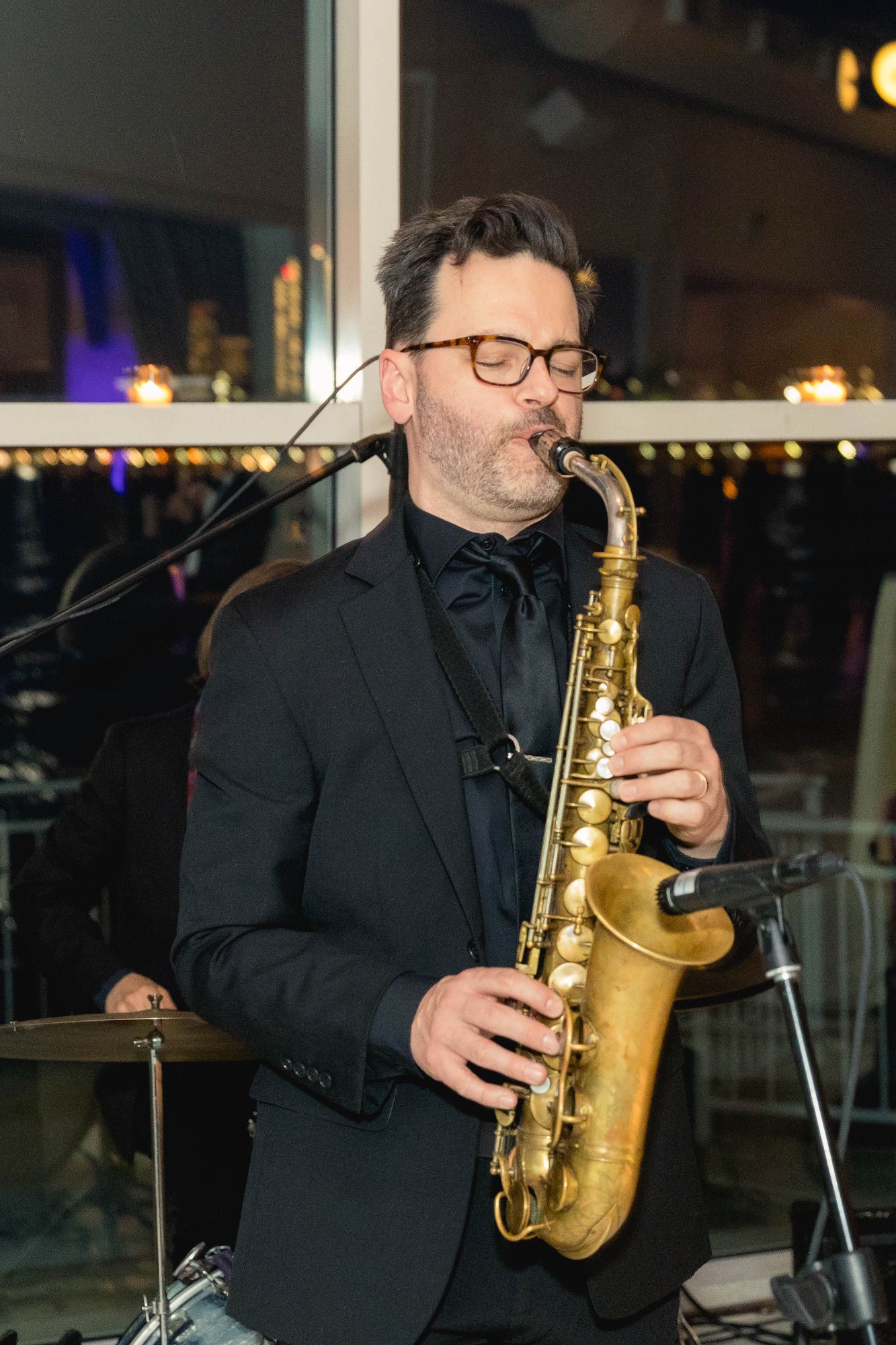 Close-up of saxophone player — eyes closed, fully absorbed in performance