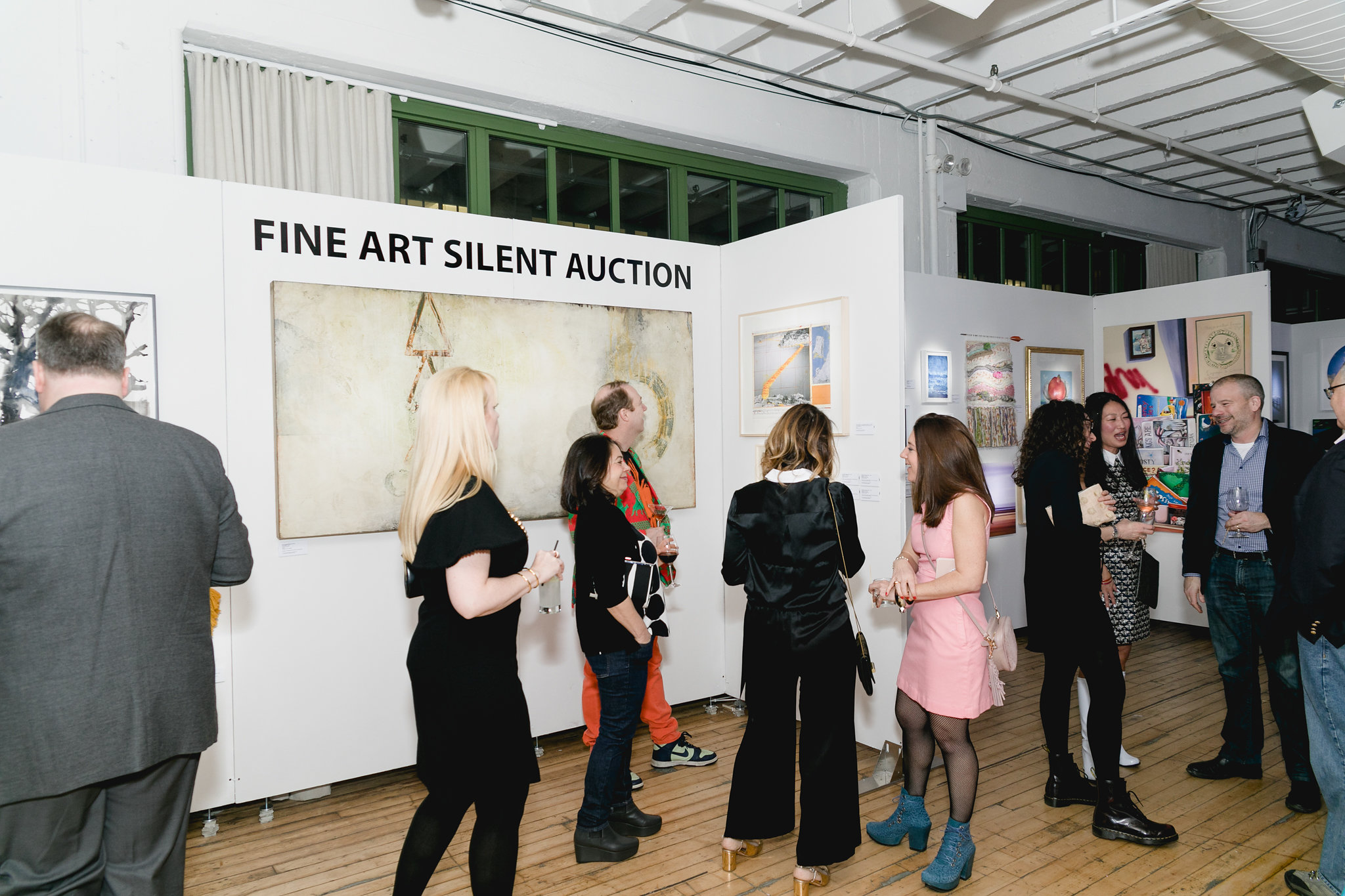 Wide venue shot — guests moving through, art on walls, the full room in motion