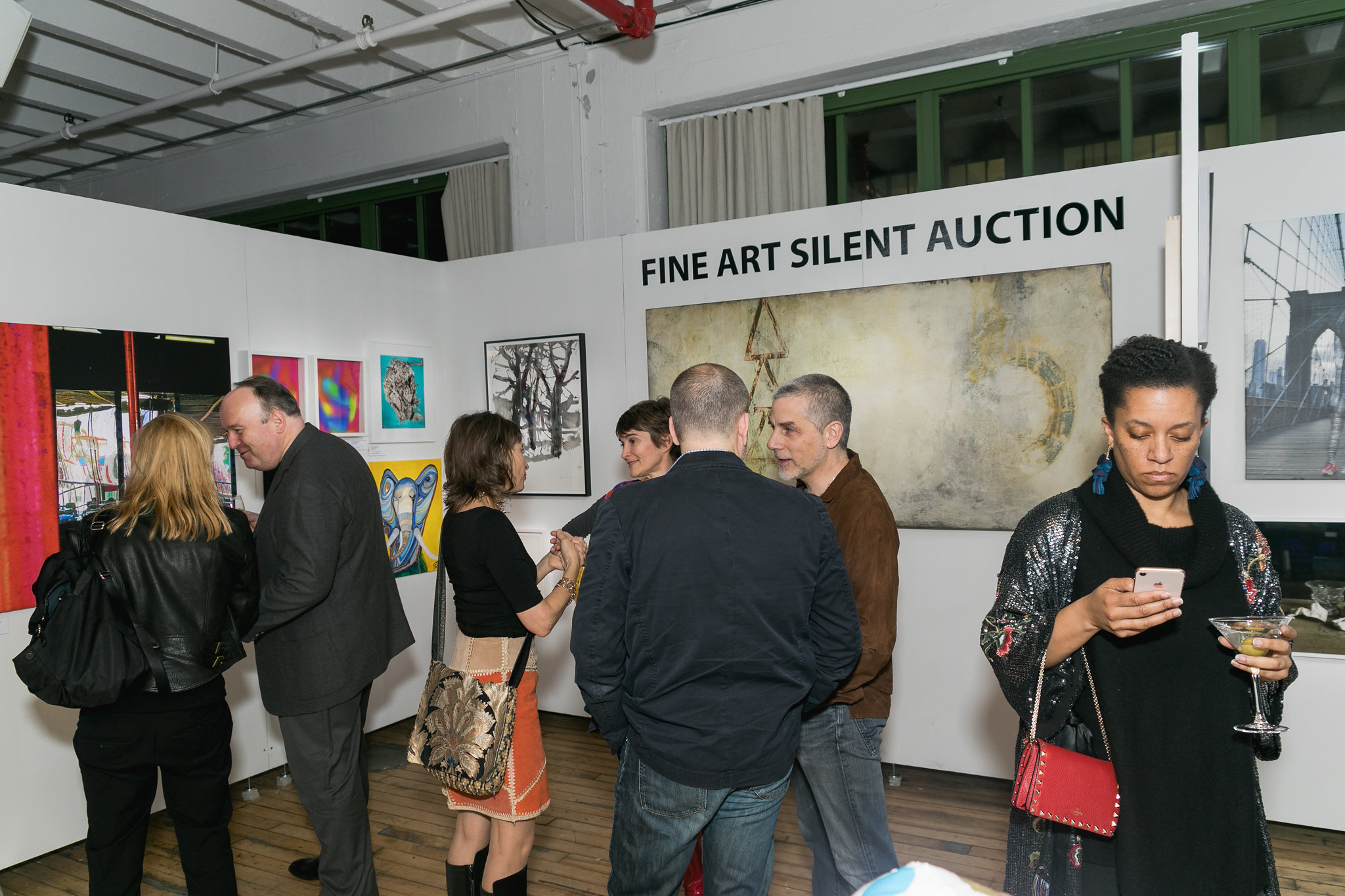 Fine Art Silent Auction signage — guests studying the works in front of painted canvases