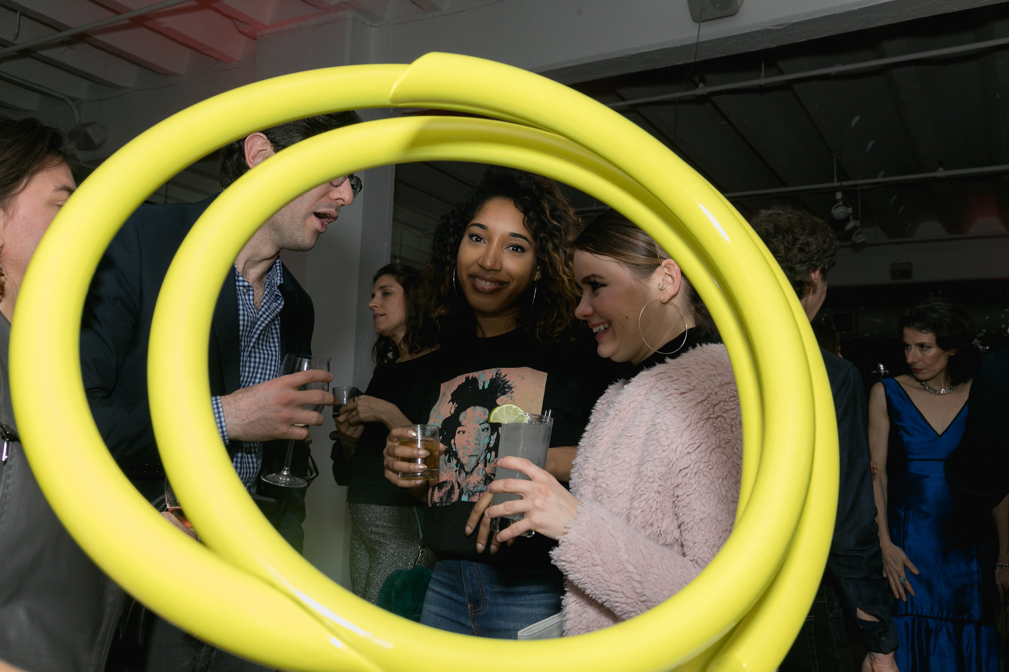 Two guests framed through a yellow ring sculpture — art and people in the same frame