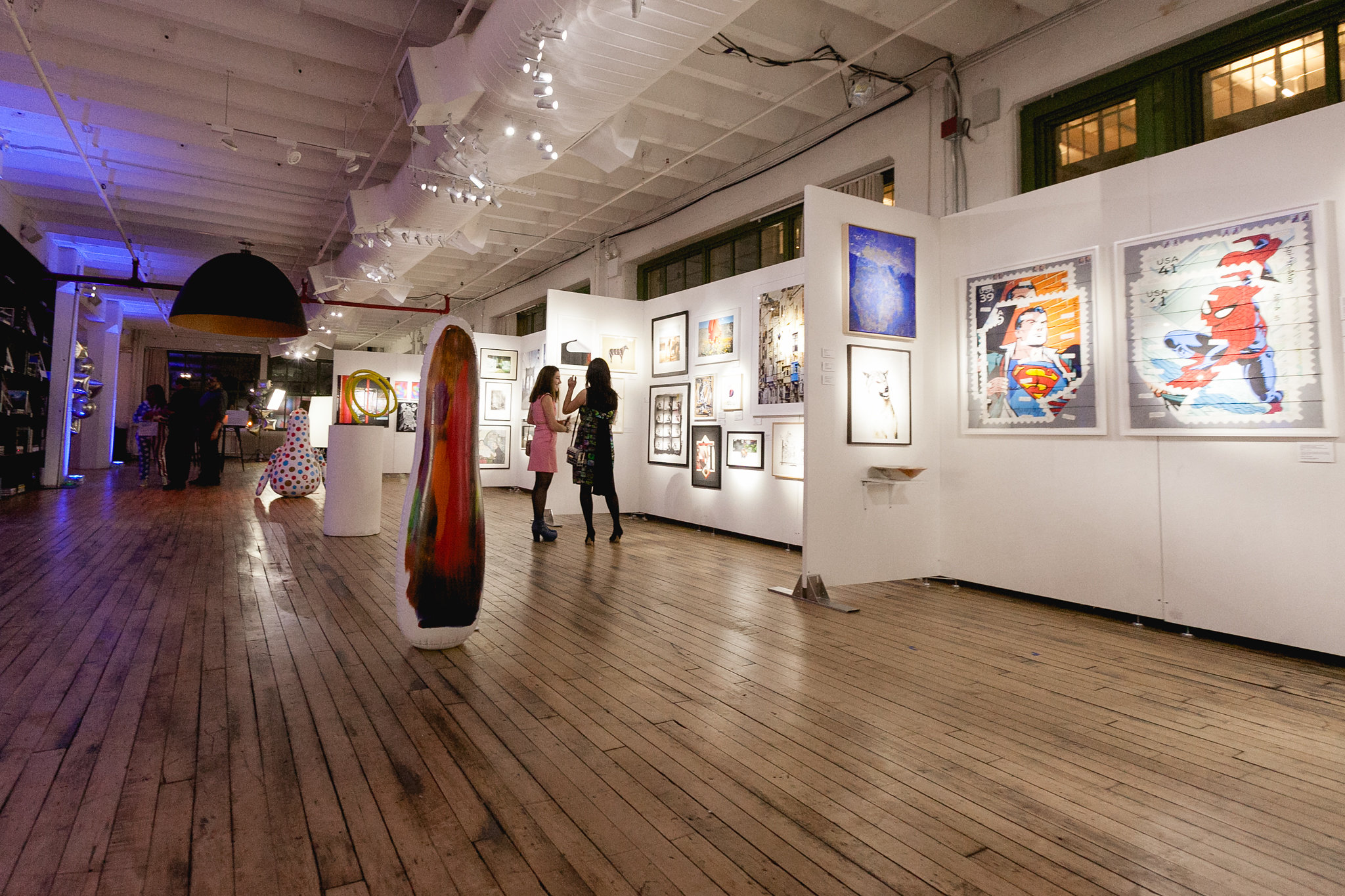 The gallery before the crowd — sculpture and paintings in full view, hardwood floors, warm light