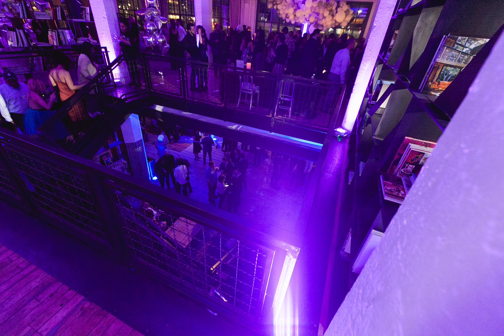 Bird's eye view from top mezzanine — purple light, full crowd below, two levels visible