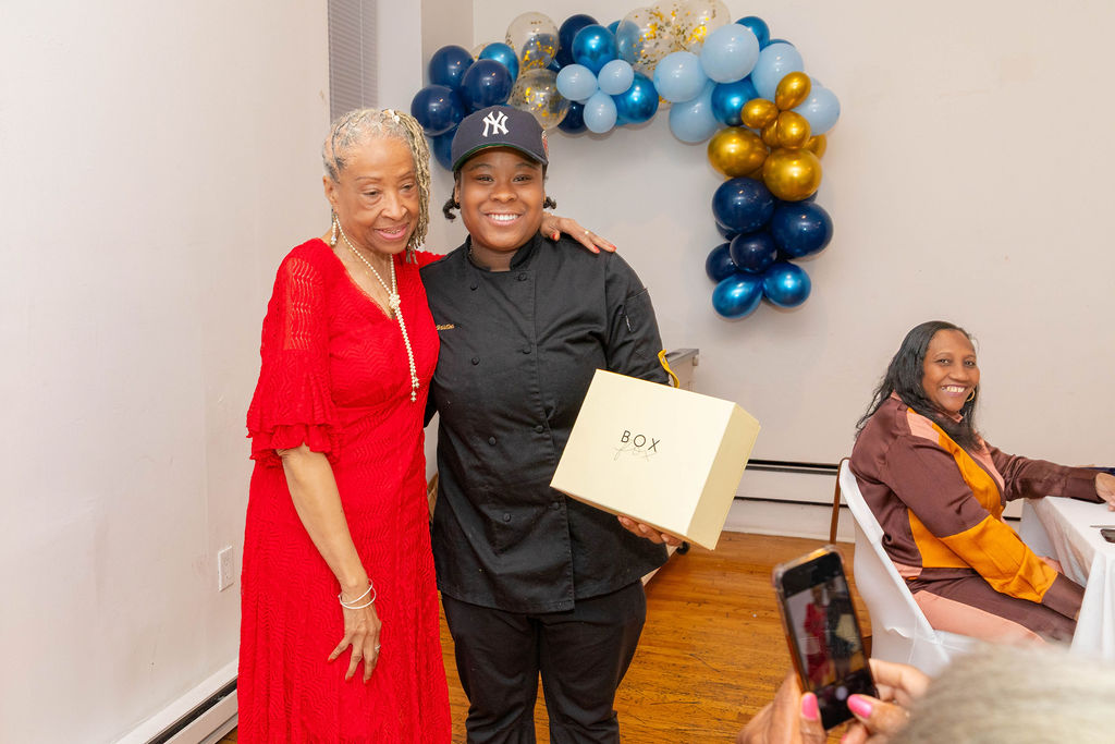 Chef presenting a gold gift box to a guest — the close of the luncheon